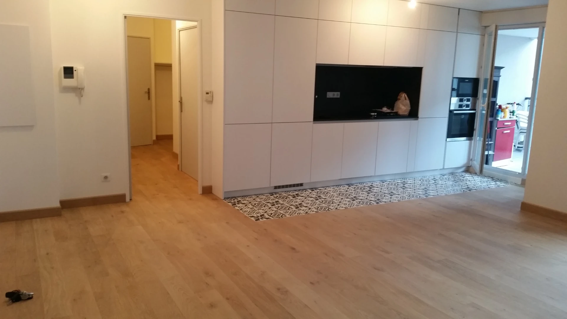 Séjour rénové avec parquet clair et cuisine blanche intégrée